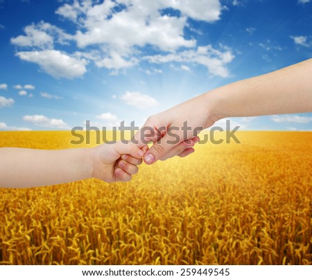 mother gives a hand of a child on landscape