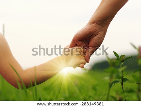 Hands of mother and daughter holding each other on field