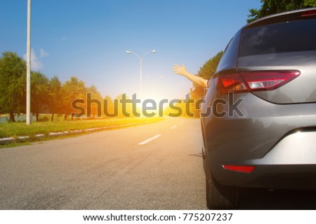 Car on asphalt road in nature. Man hand relaxing and enjoying road trip and sunny.