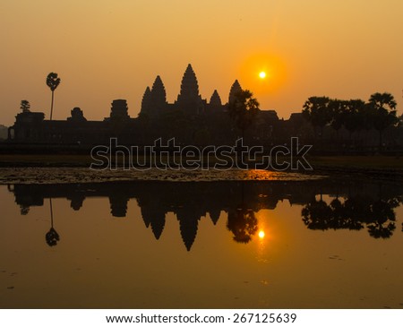 Angkor Wat at sunrise with reflection in pond. Sun rises over the ancient ruins in Siem Reap Cambodia.