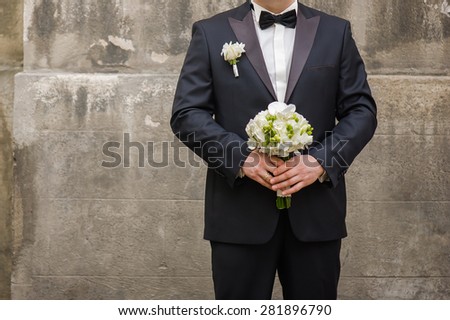 Beautiful bouquet of flowers ready for the big wedding ceremony. adult solid groom button his blue suit near wall