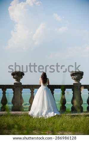 young bride before the wedding ceremony, is looking at the clouds from the balcony of a medieval castle