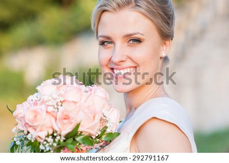 Smiling bride holding big wedding bouquet