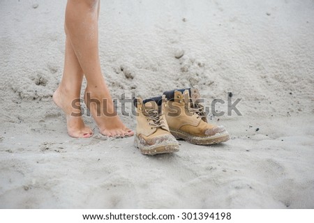 Beautiful, slim female legs in high leather boots. Girl with thick shoes on the sand
