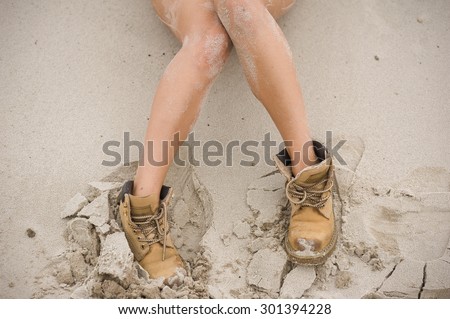Beautiful, slim female legs in high leather boots. Girl with thick shoes on the sand