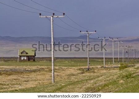 An isolated house on the Icelandic countryside. Maybe connected to the world by the telephone poles.