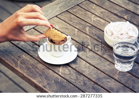 woman\'s hand dipping biscuit in Turkish coffee \