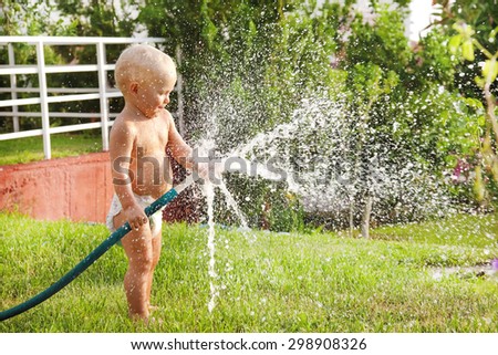 Child watering the grass in the yard