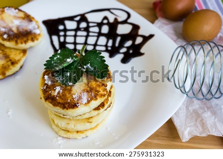 Cheesecakes with fried cheese and powdered sugar, liquid chocolate. Whisk and eggs