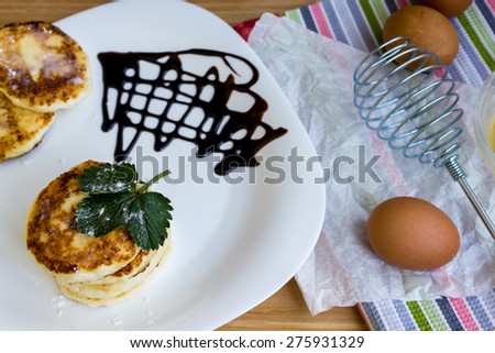 Cheesecakes with ruddy cheese and powdered sugar, liquid chocolate. Whisk and eggs