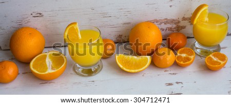 Fresh orange juice in a glass on a white wooden table. Cut slices of orange and juice.