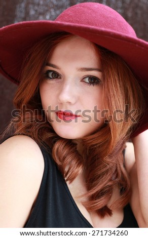 Beautiful young woman with red hair wearing a floppy hat.