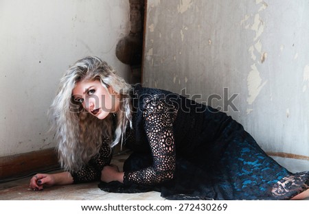 Beautiful young woman styled in a gothic style crawling on a floor
