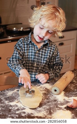 Beautiful blonde haired boy cutting out pastry