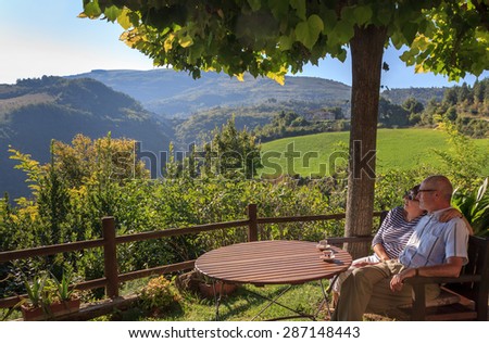 Happy couple sitting in shadow on sunny day in Tuscany, Italy