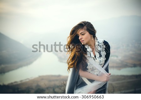beautiful girl in dress on the rocks (behind the mountains and the river)