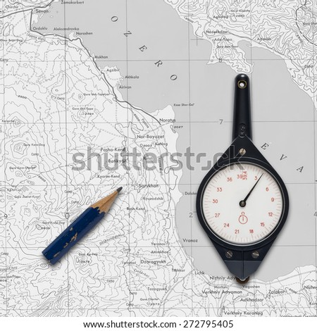 Old mechanical curvimeter over a map.\
A device for measuring the length of curves, such as on a map.\
over a map.