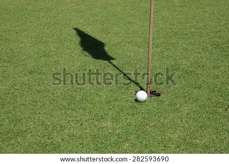 Golf ball on green meadow. golf ball on lip of cup