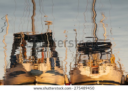 Reflections of sailing boats in calm water. Image is rotated by 180 degrees.