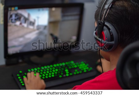 Back view of young gamer in headphone playing video game at home.