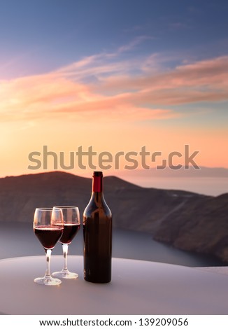 Wine bottle and glasses overlooking Santorini cliffs
