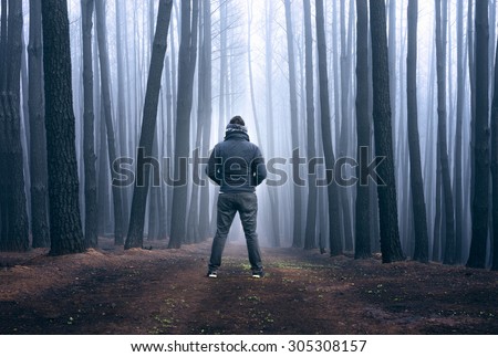 Man stares into the fog in a blackened forest