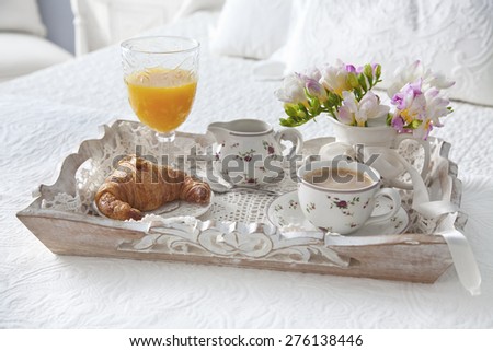 Croissant and tea with juice  on breakfast tray