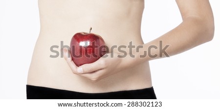 A picture of a woman holding a red apple in front of her fit belly. Isolated on white background