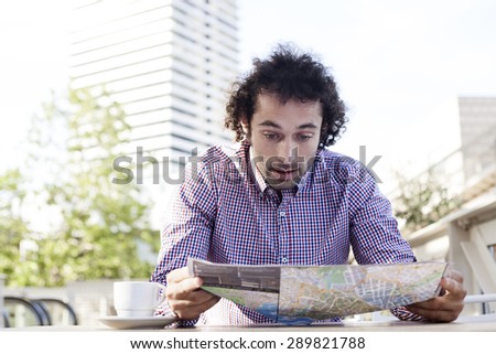 Handsome man consulting a guide in a restaurant terrace. Vacation concept.