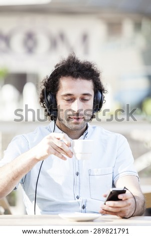 Handsome man listening to some music in a restaurant terrace