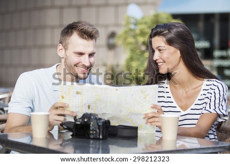 Happy couple tourists consulting a guide in a restaurant terrace. Vacation concept