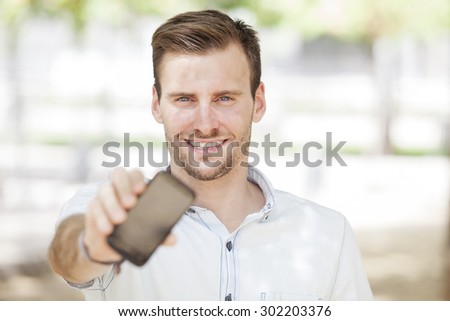Happy man showing a mobile phone screen outdoor