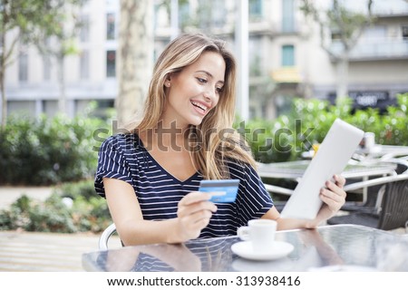 Woman buying online with a tablet and a credit card in a terrace bar