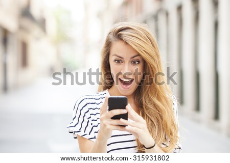 Portrait of surprised young girl looking at phone seeing news or photos with funny emotion on her face isolated outside city background. Human emotion, reaction, expression