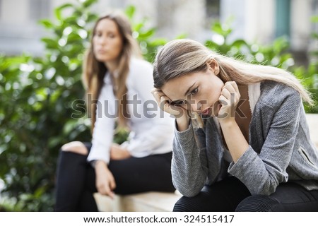 Portrait of young woman and friend outdoor on street having problems. Depression concept