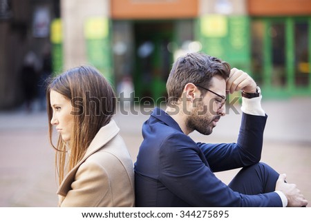 Bad relationship concept. Man and woman in disagreement. Young couple after quarrel sitting back to back. Outdoor