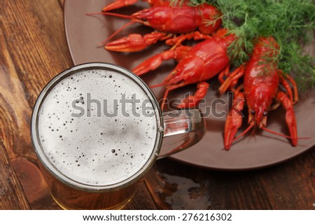 boiled crayfish on wooden surface with a beer and dill.old style plate