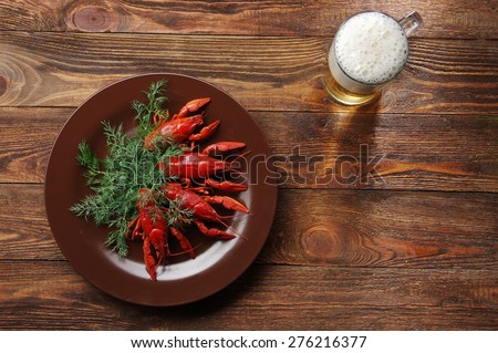 boiled crayfish on wooden surface with a beer and dill. old style plate