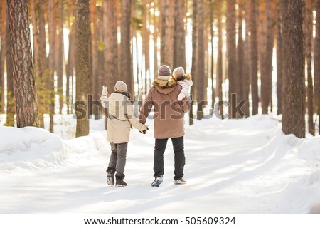 Father walks with his little daughters and teen-son in a forest in winter