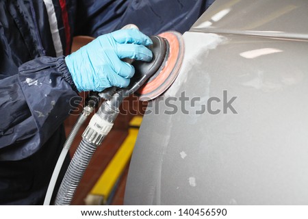 Painter polishes a car body component