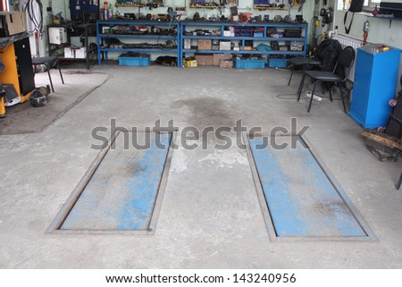Image of a car repair garage with lift in non-working position