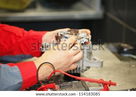 Hands of mechanic restores a generator