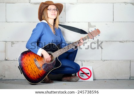 woman in a hat plays guitar