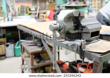 The image of a old vice on a metal workbench