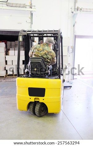 Worker driver stacking boxes by forklift stacker loader