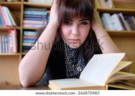 Sad female student in library looking at camera