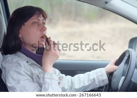 Women make up lips at the wheel the car