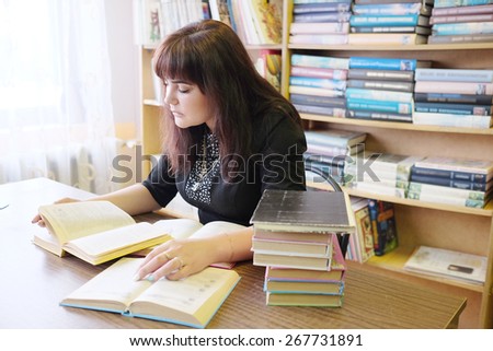 Female student reads the book in library.