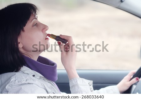 Women make up lips at the wheel the car