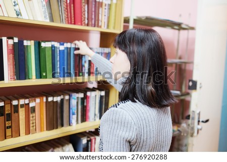 Woman in the library takes the book from the shelf